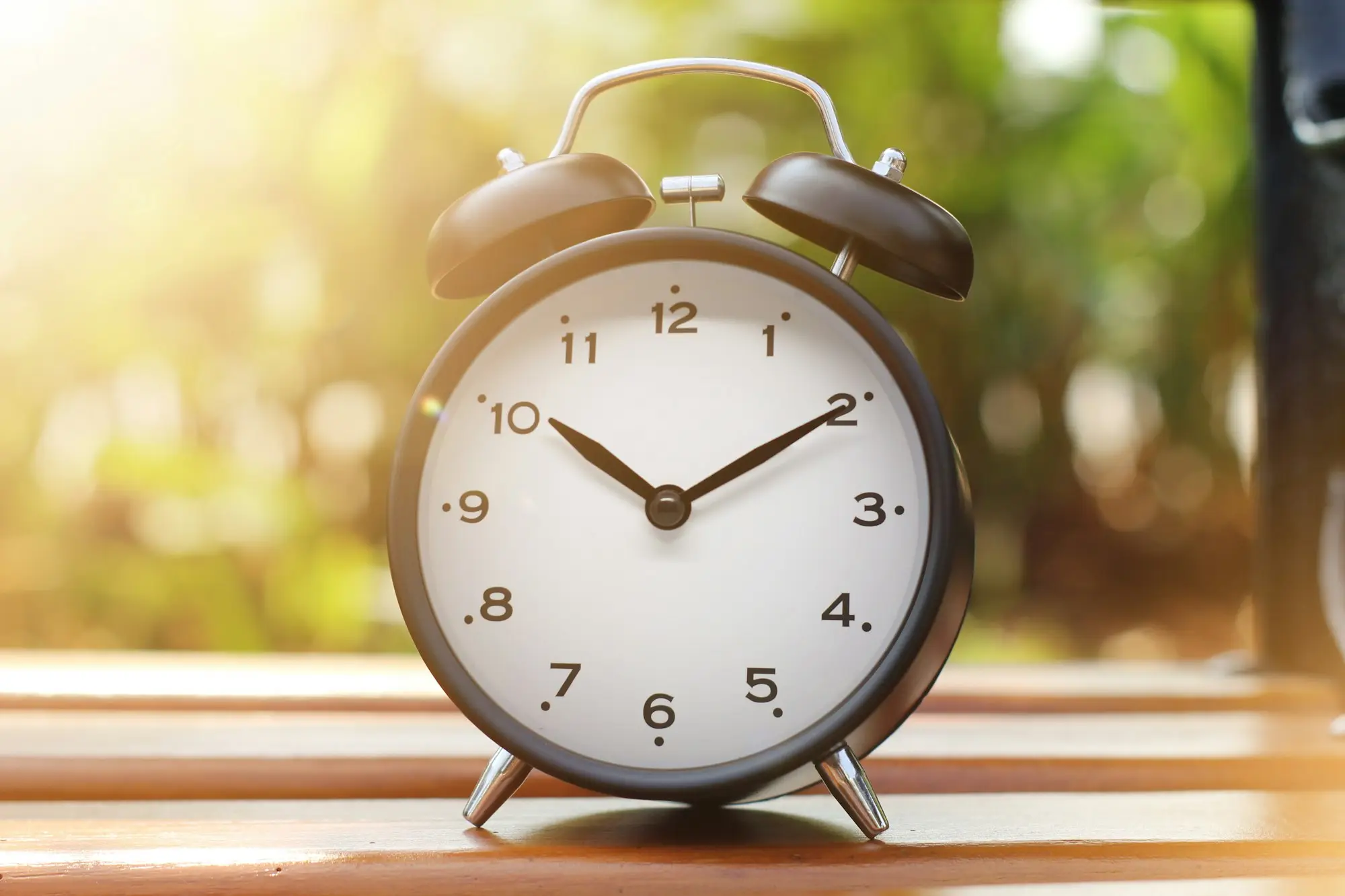 Alarm clock sitting on a wooden table, a reminder that a deadline is close
